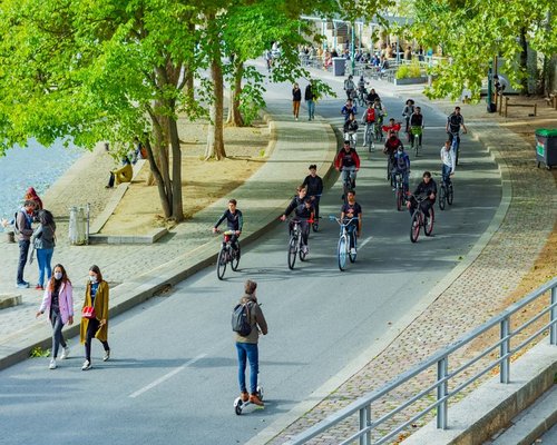 A quiet group of citizens enjoying a steady and gentle walk along a wide green bicycle lane during a temperate afternoon